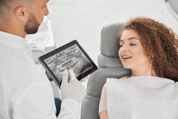 skilled-male-dentist-showing-x-ray-picture-teeth-woman